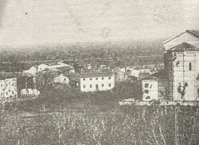 Veduta d&rsquo;epoca di Castelnovo vista dai campi: le case del paese e un edificio con il frontone sulla destra
